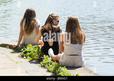 Tre giovani donne seduti su un canale banca in King's Cross, London, Regno Unito Foto Stock