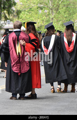 Vestito di vesti di graduazione e tappi gli studenti e i genitori che celebrare la giornata. Foto Stock