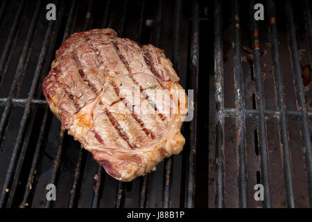 Una disseccata ribeye grigliare su un grill a gas Foto Stock