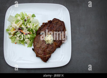 Riempito di grasso Ribeye con burro di coriandolo e un'insalata a parte e rabboccato con Ranch dressing. Perfetto per una dieta ketogenic Foto Stock