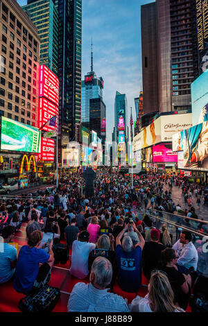 I turisti enjying su New York City Time Square di notte Foto Stock