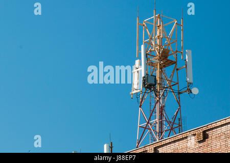 Torre di comunicazione sul tetto di un edificio contro il cielo blu Foto Stock