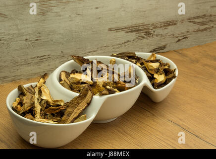 Secchi, aromatici funghi di bosco in una ciotola bianco su una cucina in legno tavolo. Ideale per minestre e piatti vari. Vista orizzontale. Foto Stock