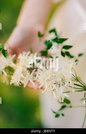 Gli anelli di nozze i fiori di gelsomino nelle mani della sposa. Gioielli di nozze. Foto Stock