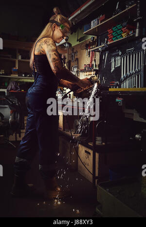Donna meccanico che lavora in un laboratorio del motociclo Foto Stock