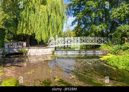 Un ponte decorativo oltre le chiare acque del fiume Frome come fluisce attraverso i motivi della Casa Athelhampton, Dorset, Inghilterra Foto Stock