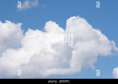 Close up del bianco e del grigio soffici nuvole contro medio cielo blu. Foto Stock