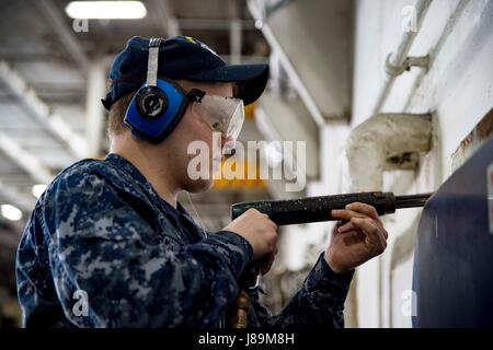 170522-N-QN175-038 Norfolk, Virginia (22 maggio 2017) di aviazione di Boatswain Mate (manipolazione) Airman Logan Schinabeck pistole ad aghi di un portello telaio nella baia di hangar della portaerei USS Dwight D. Eisenhower CVN (69) (IKE). Ike è attualmente pier lato durante la fase di supporto della flotta ottimizzato il piano di risposta (OFRP). (U.S. Foto di Marina di Massa lo specialista di comunicazione di terza classe Dartez C. Williams) Foto Stock