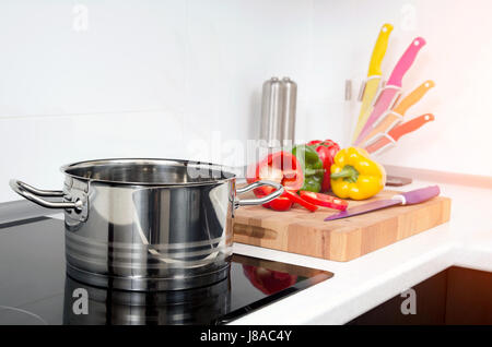 Pentola e verdure in cucina moderna con fornelli a induzione. Stufa fornello da cucina pan pot in acciaio concetto gourmet Foto Stock