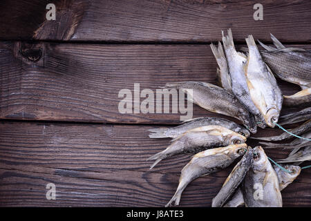 Pesce conservato la RAM è legato con una corda su un legno marrone di sfondo, lo spazio vuoto sulla sinistra Foto Stock