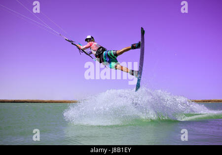 Professional kite boarding rider sportivo salta di alta acrobazia kiteboarding raley trucco con un enorme spruzzo d'acqua. Attività ricreative e di estrema Foto Stock