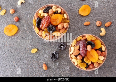 Due moduli cartacei con un mix di frutta secca e i dadi su sfondo di pietra Foto Stock