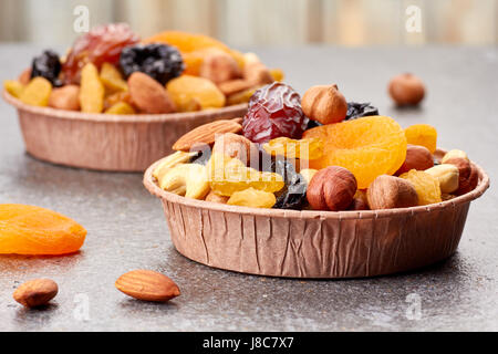 I moduli cartacei con un mix di frutta secca e i dadi su sfondo di pietra Foto Stock