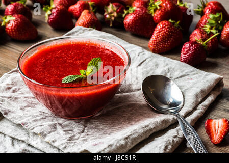 Una ciotola di salsa di fragole con un cucchiaio su un tessuto di lino igienico Foto Stock