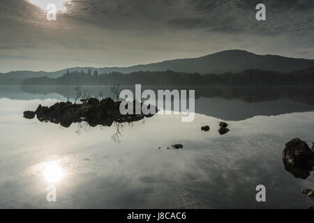 Nebbiosa mattina autunnale con riflessioni in Coniston Water nel Lake District inglese, Regno Unito Foto Stock