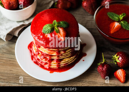 Close-up american pancake e salsa di fragole su uno sfondo di legno. Profondità di campo. Foto Stock
