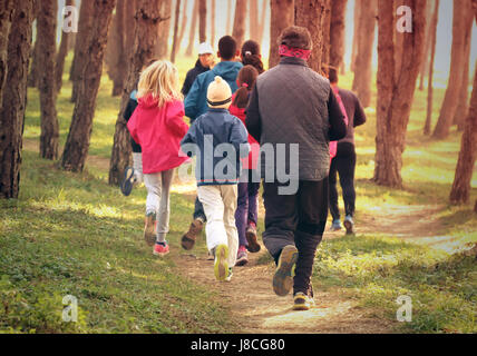 Gruppo di persone in esecuzione su sterrato percorso attraverso la foresta Foto Stock