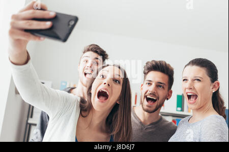 Allegro adolescenti tenendo autoritratti usando un touch screen smart phone, la condivisione e il concetto di tecnologia Foto Stock