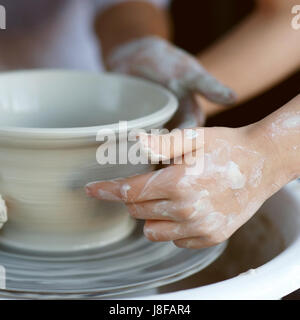 Madre figlio insegna a lavorare sulla ruota di ceramiche. Close up di mani sporche scultura in argilla. Foto Stock