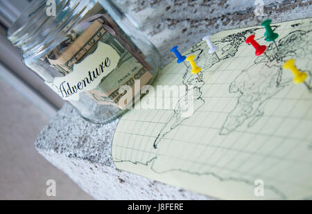 Un vaso di vetro con il denaro messo da parte per una vacanza con la scritta "avventura" Foto Stock