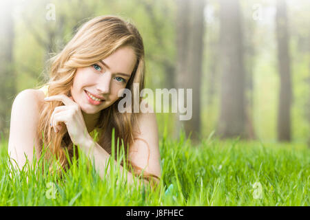 Rossa o bionda romantica bella giovane donna posa su erba nel parco Foto Stock