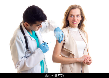 Bel giovane medico con i capelli neri in abito bianco con uno stetoscopio e guanti blu facendo una iniezione di piacevole giovane donna con capelli lunghi marrone Foto Stock