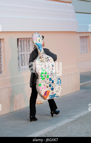 Una donna che porta il suo violoncello attraverso le strade della Croazia Foto Stock