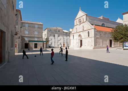 I bambini che giocano a calcio davanti a una chiesa medievale in Rab Croazia Foto Stock