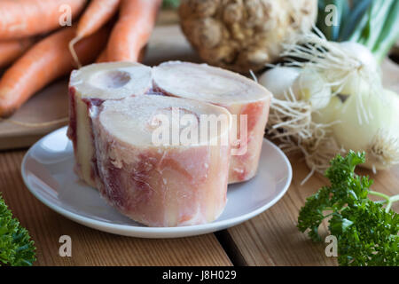 Ingredienti per la realizzazione di un osso di manzo in brodo - ossibuchi, carote, cipolle, prezzemolo e radice di sedano Foto Stock