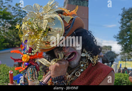 Un esecutore morde la parte superiore di un contenitore per confetti durante una parata galattico in Costa Rica del Festival Internacional de Arte, o la FIA, in data 4 aprile 201 Foto Stock