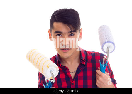 Giovane uomo attraente con i capelli neri in rosso plaid shirt holding rotoli colorati su sfondo bianco in studio Foto Stock