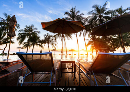 Splendida spiaggia tropicale paesaggio di destinazione di lusso con piscina e palme di cocco vicino al mare al tramonto Foto Stock