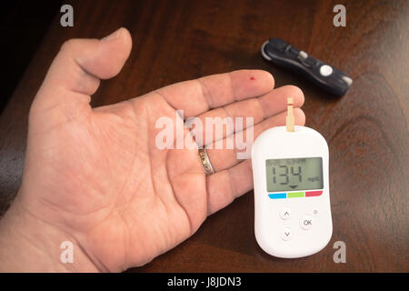 Tester digitale indica la presenza di un livello di glucosio nel sangue di 134 Foto Stock