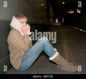 Triste giovane donna seduta su strada Foto Stock