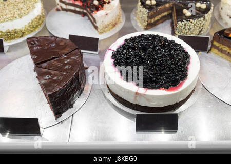 Diversi tipi di torte in una pasticceria display in vetro Foto Stock