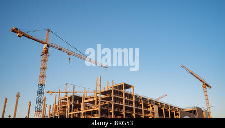 Sito in costruzione con molte gru nella luce di sunrise. Costruzione di concetto di sviluppo Foto Stock