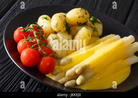 Deliziosa casa asparagi con salsa olandese, freschi patate e pomodori freschi di close-up su una piastra orizzontale. Foto Stock