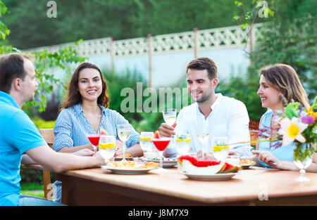 Gruppo di amici felice tostatura di bicchieri di vino in giardino mentre a pranzo Foto Stock