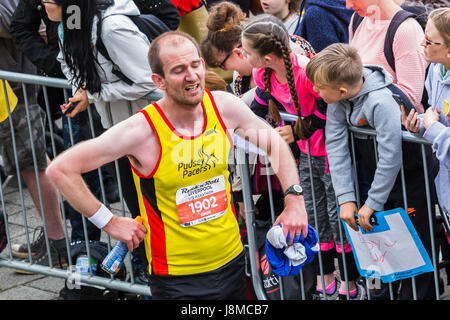 Una mezza maratona runner attraversa la linea di finitura dalla Liverpool Echo Arena del 28 maggio 2017 avente correva nel 2017 Liverpool Rock n Roll marathon. Foto Stock