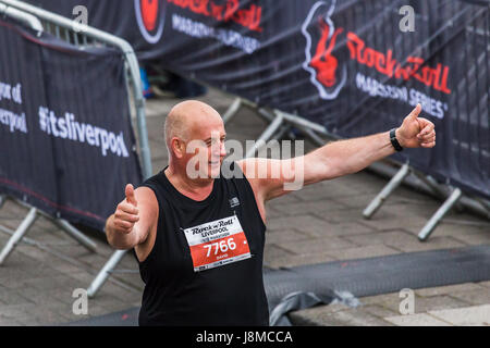 Una mezza maratona runner attraversa la linea di finitura dalla Liverpool Echo Arena del 28 maggio 2017 avente correva nel 2017 Liverpool Rock n Roll Half maratho Foto Stock