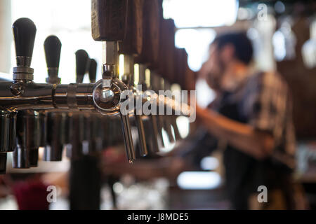 Sacco di vintage Golden rubinetti di birra nel bar con il barista in background Foto Stock