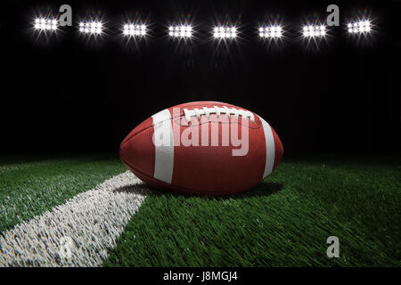 Basso angolo di visualizzazione stile college football su un cortile di linea di un campo di calcio sotto le luci dello stadio Foto Stock