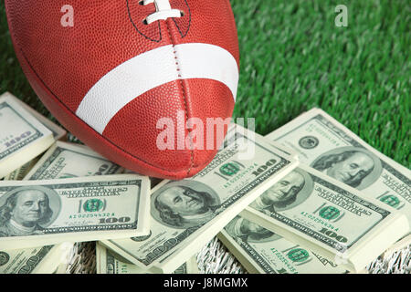 Un stile college football si siede con un mucchio di soldi su un campo verde Foto Stock