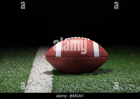 College Football di stile sul campo in erba e striscia di notte angolo basso Foto Stock