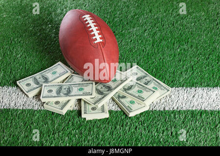 Un NFL Football si siede con un mucchio di soldi su un campo verde Foto Stock