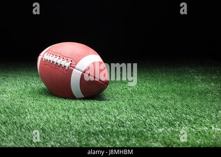 College Football di stile sul campo in erba contro uno sfondo scuro Foto Stock