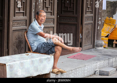 Yantou, Yongjia, Zhejiang, Cina. Uomo di mezza età seduto alla sua porta. Foto Stock