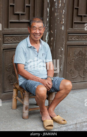 Yantou, Yongjia, Zhejiang, Cina. Uomo di mezza età seduto alla sua porta. Foto Stock