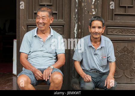 Yantou, Yongjia, Zhejiang, Cina. Di mezza età uomini seduti sulle loro porte. Foto Stock