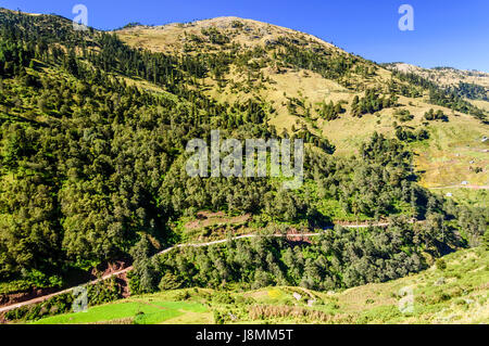 Strada si snoda attraverso colline boschive nelle Highlands di Huehuetenango, Guatemala, America centrale Foto Stock